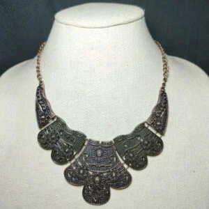 antiqued brass and copper plates connect below the collar.Features an adjustable clasp closure