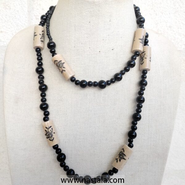 A necklace with black beads and beige floral patterned accents | قلادة مع خرز أسود وتفاصيل مزخرفة بالأزهار باللون البيج