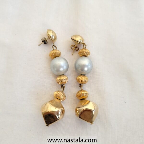 A pair of vintage earrings with metallic accents and faux pearls | أقراط عتيقة مع تفاصيل معدنية ولؤلؤ صناعي