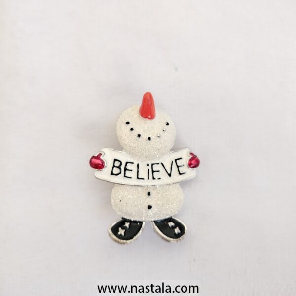 A festive snowman pin with a "Believe" banner | دبوس مزخرف على شكل رجل ثلج مع لافتة "Believe"