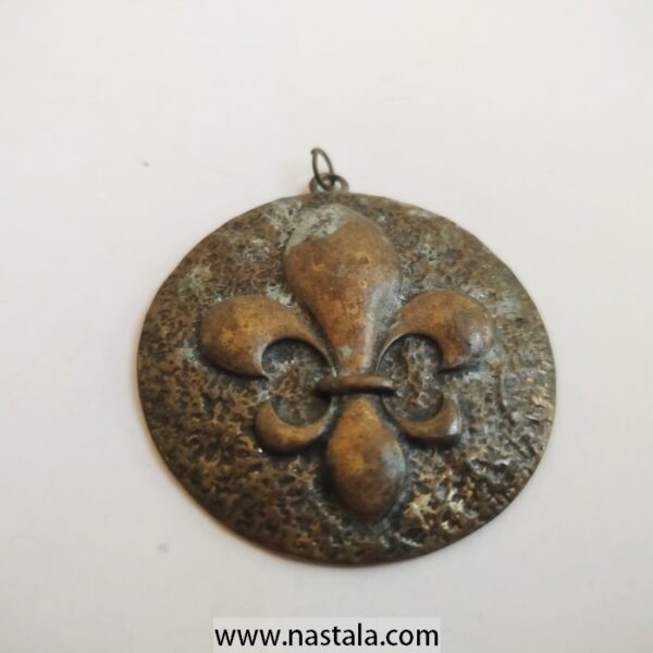 A vintage scout medal with a fleur-de-lis design | ميدالية كشافة قديمة بتصميم زهرة الزنبق