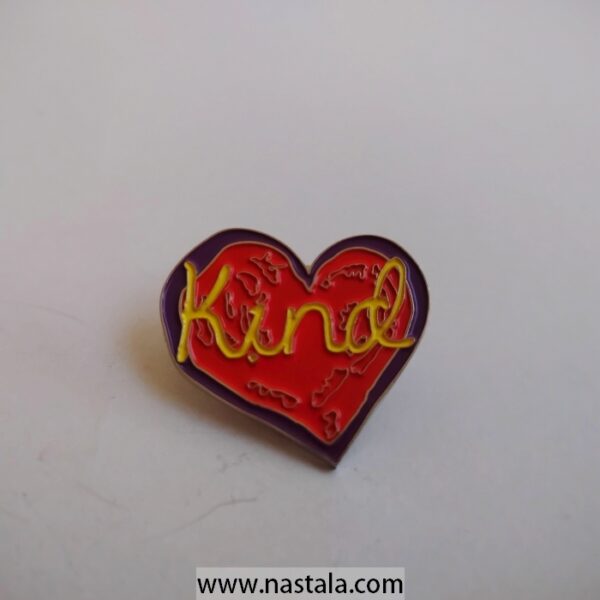 A heart-shaped pin with the word "Kind" | دبوس على شكل قلب مع كلمة "Kind"